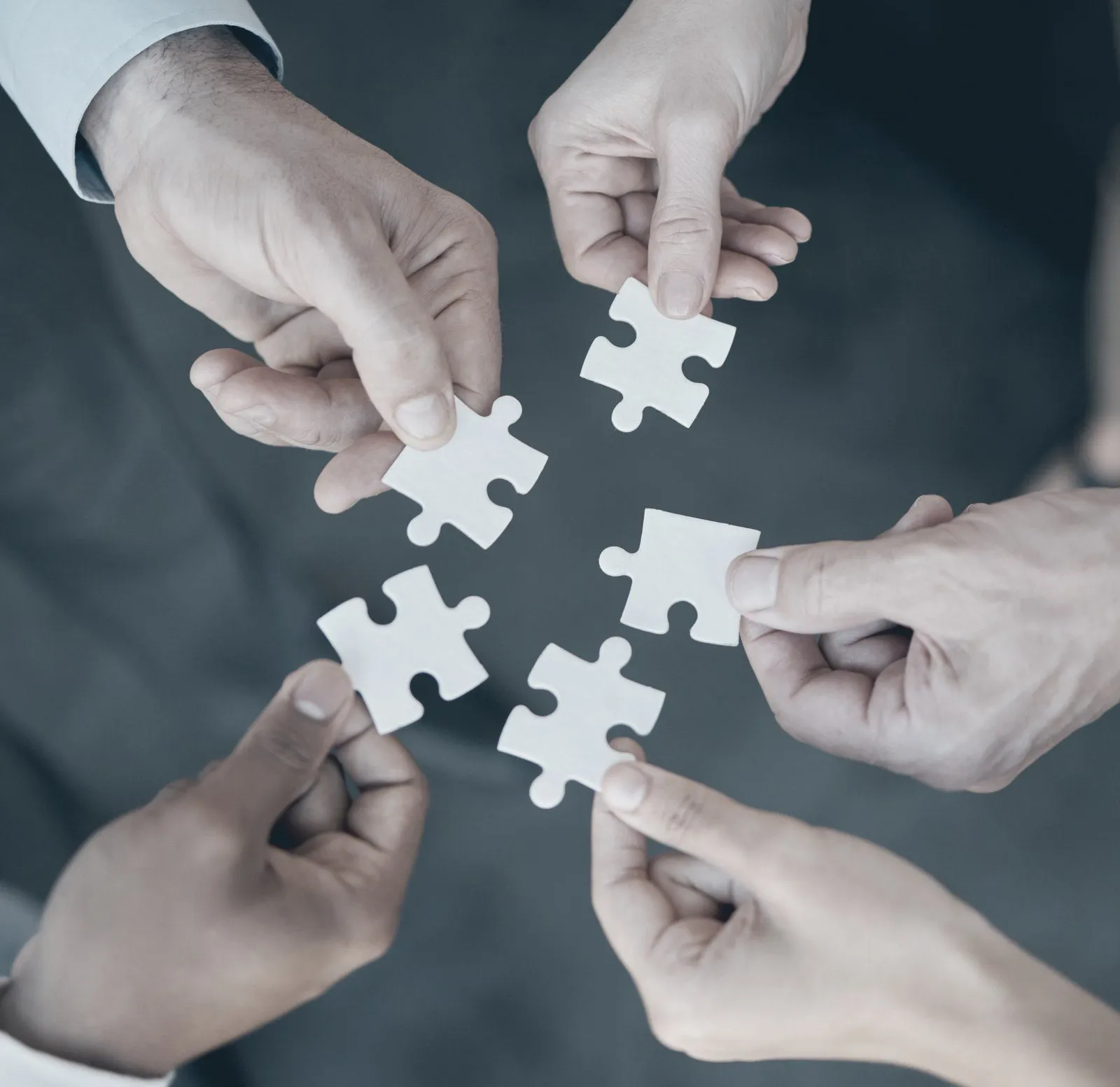 Plusieurs mains assemblent des pièces de puzzle