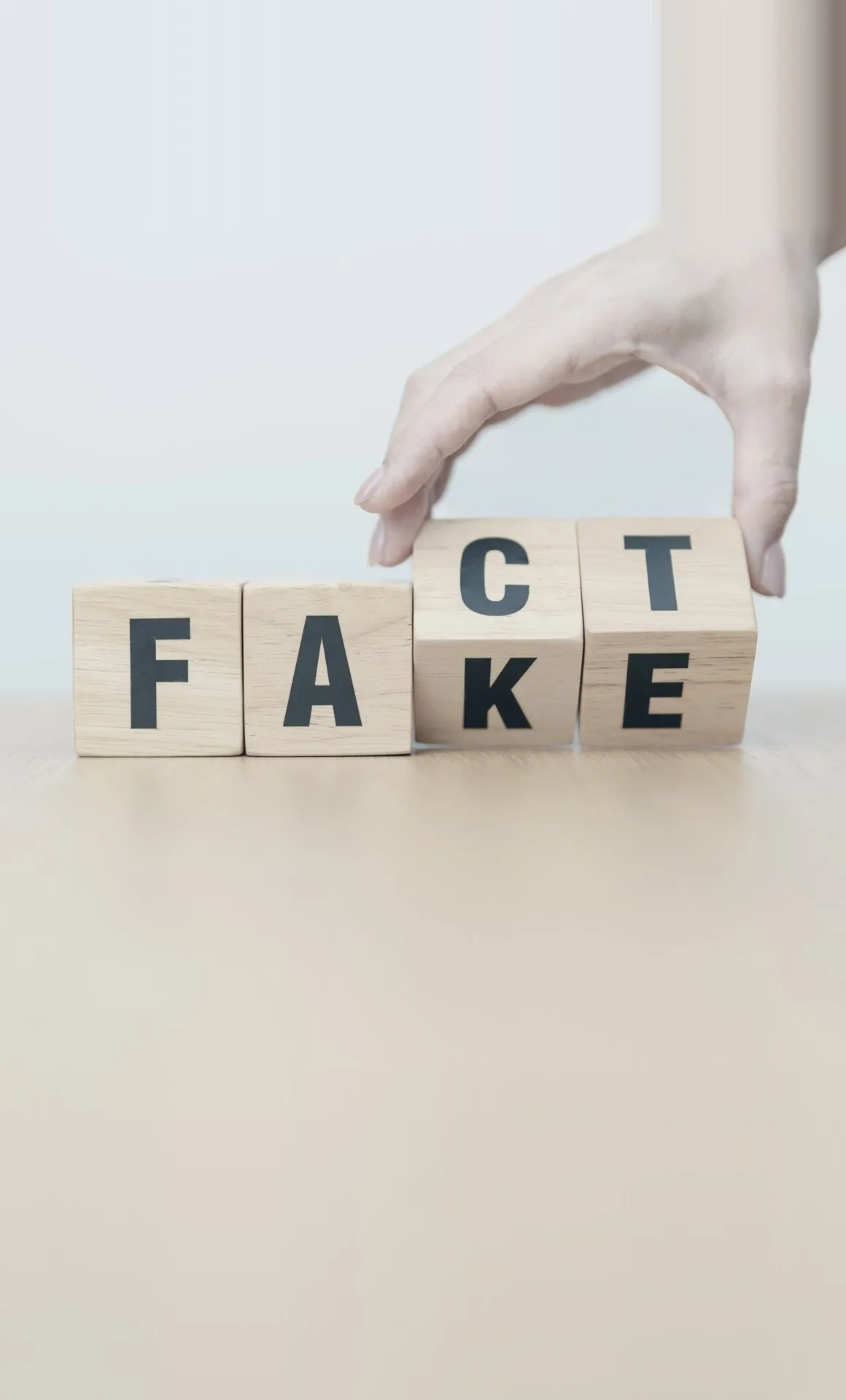 Une main retourne des cubes : FAKE devient FACT